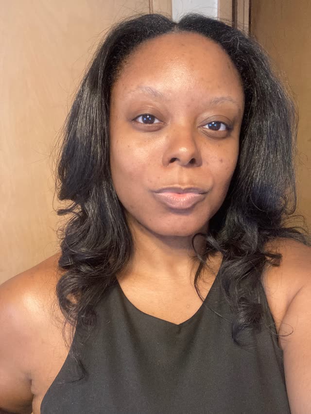 Amberly R. Carter-Mills, founder and descendant archivist of BEFORE TILL: a Black woman with long dark hair in a black sleeveless top, photographed indoors against a warm tan background.